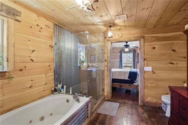 full bathroom featuring plus walk in shower, hardwood / wood-style flooring, wooden walls, ceiling fan, and toilet