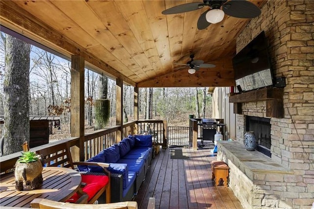 sunroom / solarium featuring an outdoor stone fireplace, wooden ceiling, ceiling fan, and vaulted ceiling