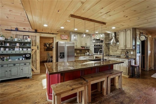 kitchen with hardwood / wood-style floors, stainless steel appliances, wall chimney exhaust hood, a kitchen island with sink, and wooden ceiling