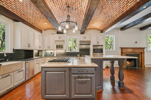 kitchen featuring appliances with stainless steel finishes, brick ceiling, a sink, a chandelier, and a fireplace