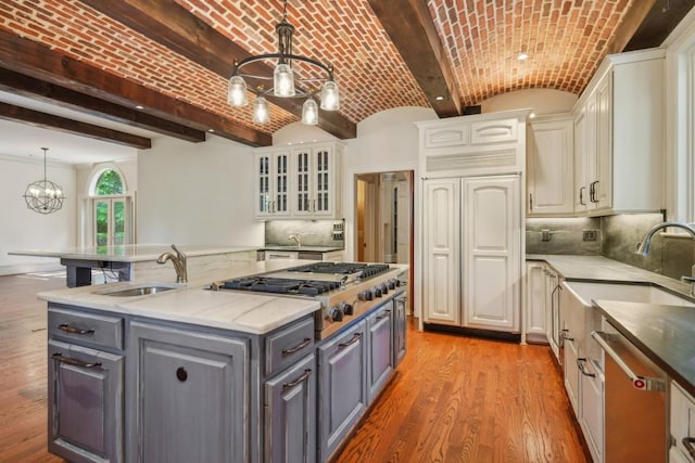 kitchen with a sink, gray cabinets, stainless steel appliances, a center island, and a chandelier