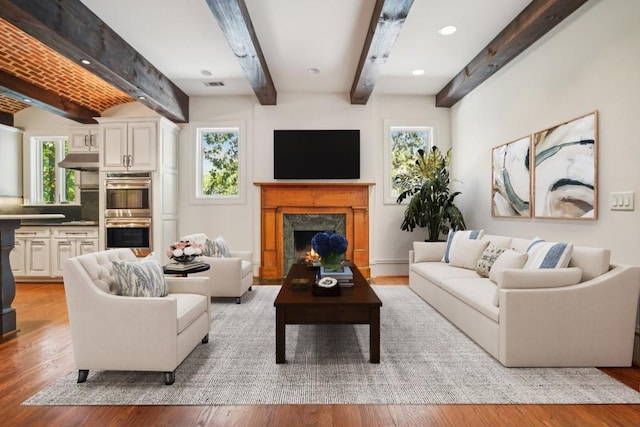 living room featuring beamed ceiling, healthy amount of natural light, a high end fireplace, light wood finished floors, and recessed lighting