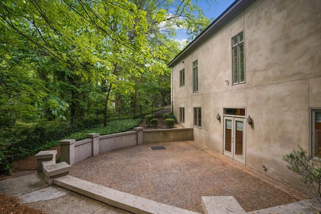 view of home's exterior with stucco siding, french doors, a patio, and fence