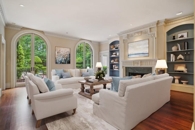 living area featuring healthy amount of natural light, a premium fireplace, ornamental molding, wood finished floors, and built in features