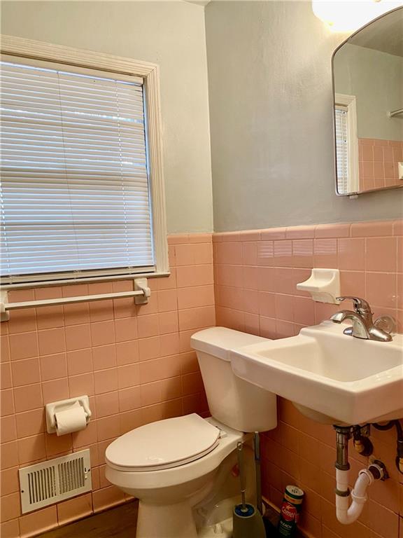 bathroom featuring tile walls and toilet