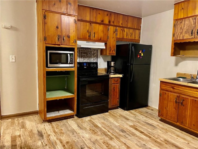 kitchen with black appliances, light hardwood / wood-style floors, and sink