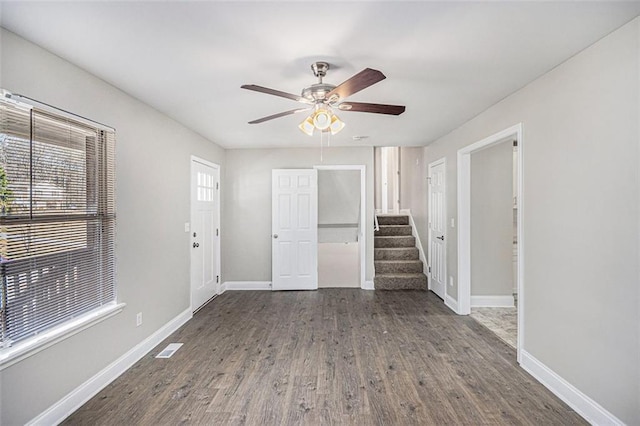 spare room with a healthy amount of sunlight, dark wood-style floors, baseboards, and stairway