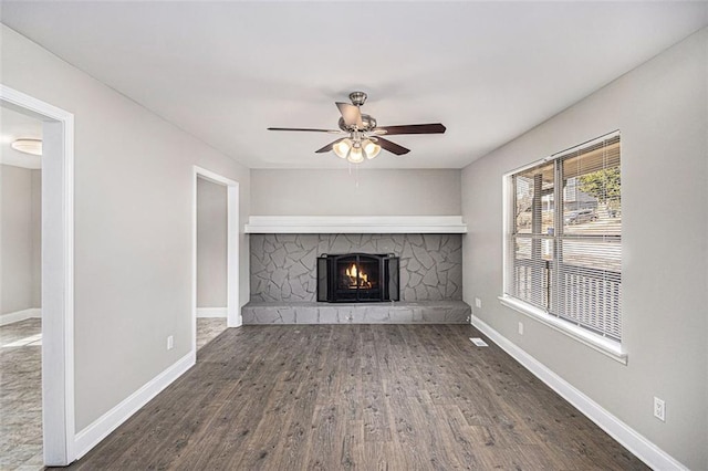 unfurnished living room with ceiling fan, dark wood-style flooring, a fireplace, and baseboards