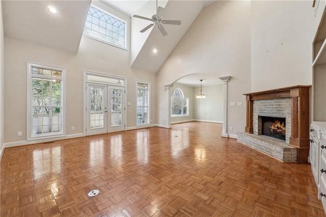 37 Long Branch Way, Dahlonega, GA 30533 - unfurnished living room with ceiling fan with notable chandelier, a fireplace, arched walkways, a high ceiling, and baseboards