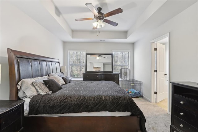 carpeted bedroom featuring ceiling fan and a tray ceiling