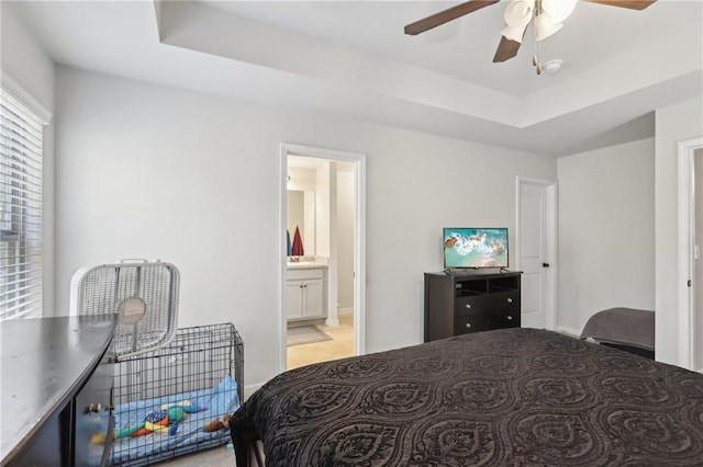 bedroom featuring ceiling fan, ensuite bathroom, and a raised ceiling