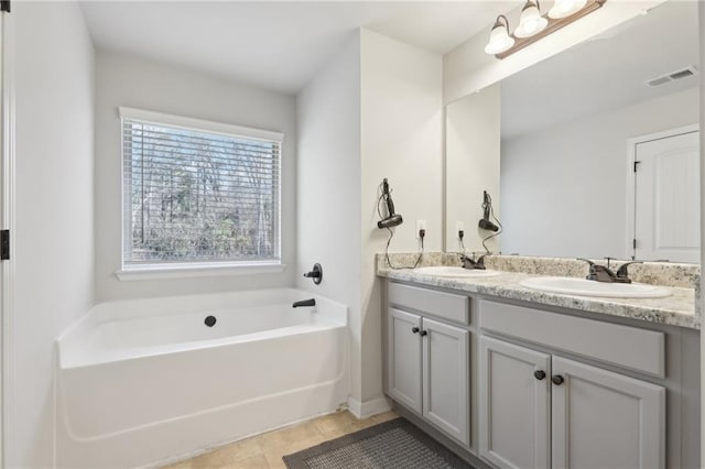 bathroom with a tub to relax in, vanity, and tile patterned flooring