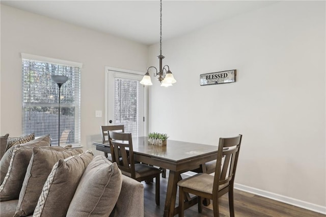 dining space featuring dark wood-type flooring and an inviting chandelier