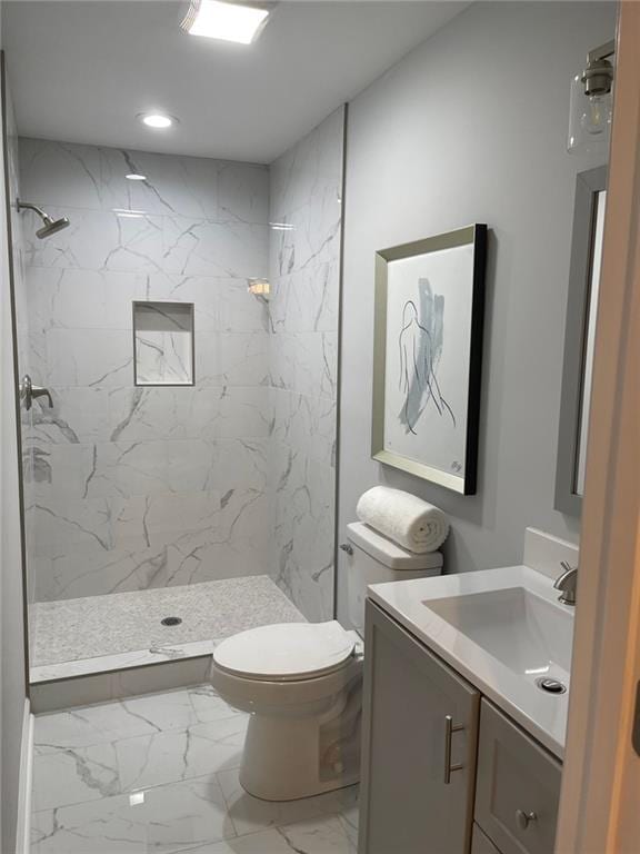 bathroom with vanity, tiled shower, and toilet