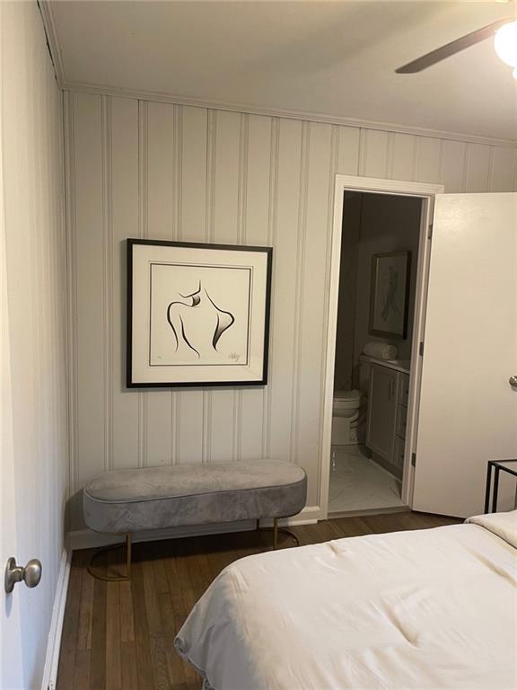 bedroom with dark wood-type flooring, ceiling fan, and connected bathroom