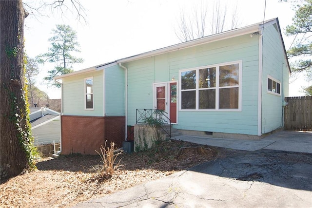 view of front facade with crawl space, brick siding, and fence