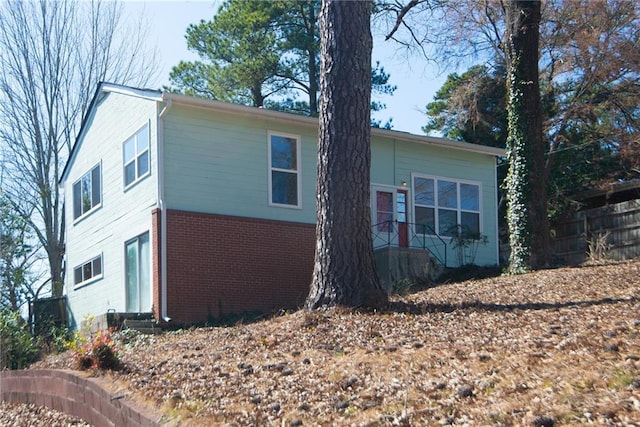 view of side of home featuring brick siding and fence