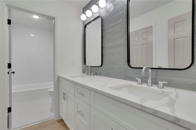 4717 Westhampton Dr, Tucker, GA 30084 - full bath featuring double vanity, toilet, tasteful backsplash, and wood finished floors