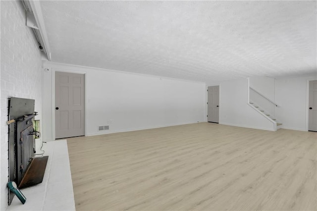 4717 Westhampton Dr, Tucker, GA 30084 - unfurnished living room featuring a textured ceiling, light wood-type flooring, stairs, a fireplace, and baseboards