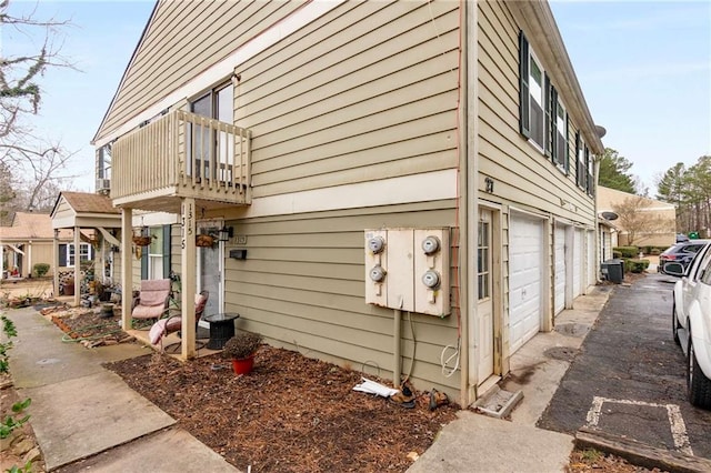 view of side of home featuring a garage, a balcony, and central air condition unit