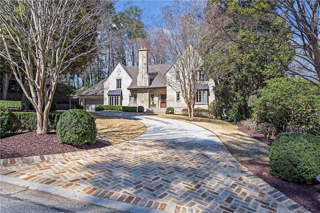 view of front of home with decorative driveway and a chimney