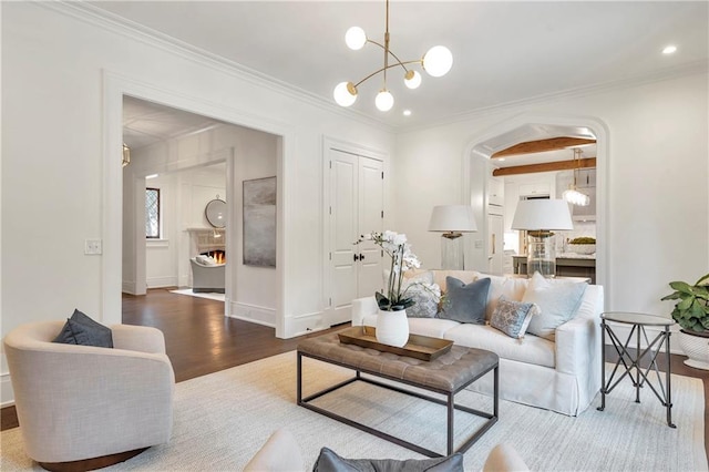 living area with an inviting chandelier, baseboards, crown molding, and wood finished floors