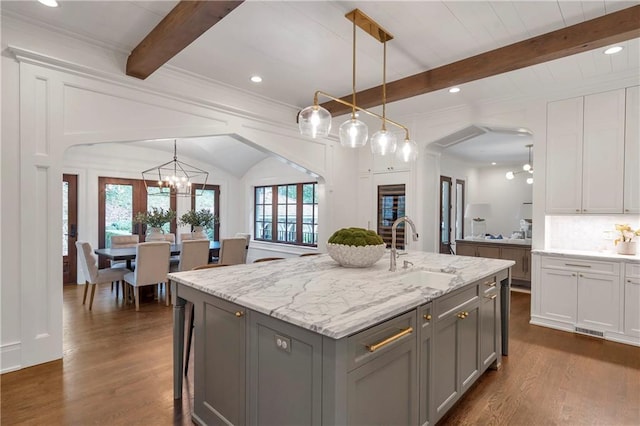 kitchen with tasteful backsplash, dark wood finished floors, a sink, gray cabinetry, and beam ceiling