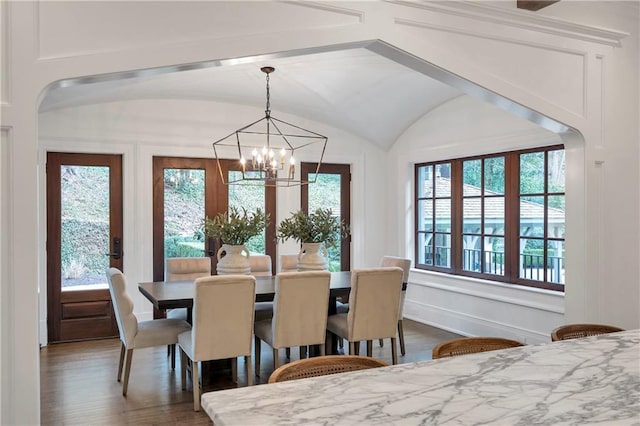 dining area featuring lofted ceiling, a notable chandelier, baseboards, and wood finished floors