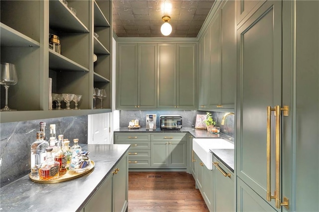 kitchen featuring green cabinets, decorative backsplash, and a sink