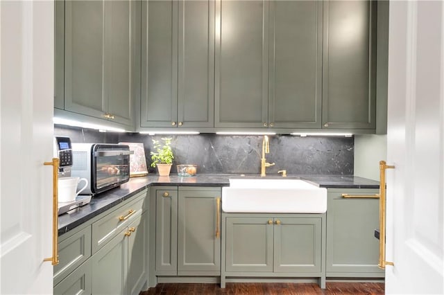 kitchen with dark countertops, a toaster, a sink, and decorative backsplash