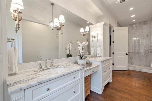 bathroom featuring a tile shower, wood finished floors, vanity, and crown molding