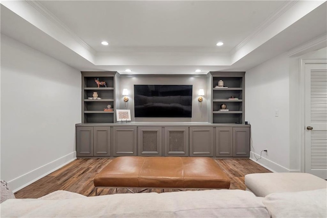 living room with baseboards, a raised ceiling, crown molding, and wood finished floors