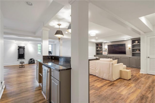 kitchen with built in features, open floor plan, beverage cooler, and wood finished floors