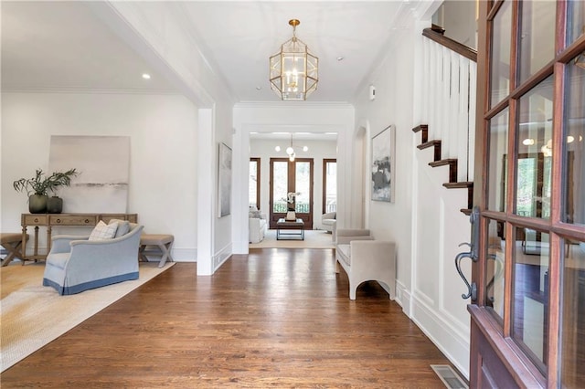 foyer featuring a chandelier, visible vents, stairs, ornamental molding, and dark wood finished floors