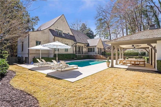 view of swimming pool with a ceiling fan, outdoor lounge area, a patio, and fence