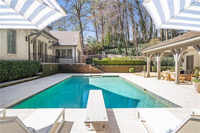 view of swimming pool featuring a fenced in pool, a diving board, a patio, and fence