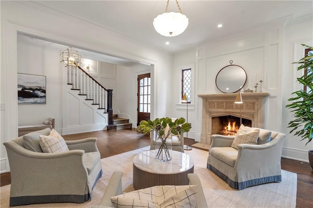 living room featuring a decorative wall, wood finished floors, a high end fireplace, stairs, and crown molding