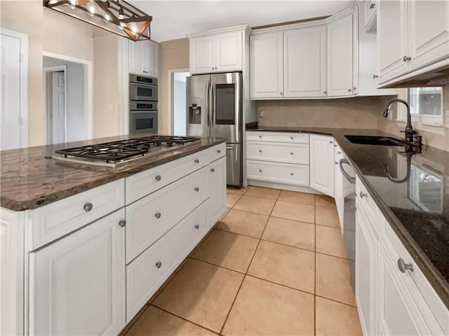 kitchen featuring dark stone countertops, white cabinets, hanging light fixtures, and stainless steel appliances