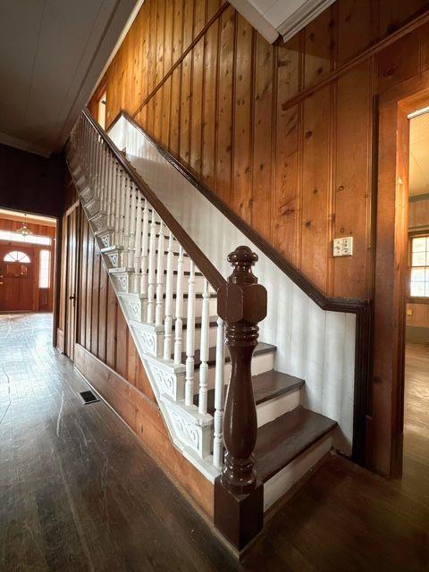 staircase featuring wood-type flooring, a high ceiling, and wood walls