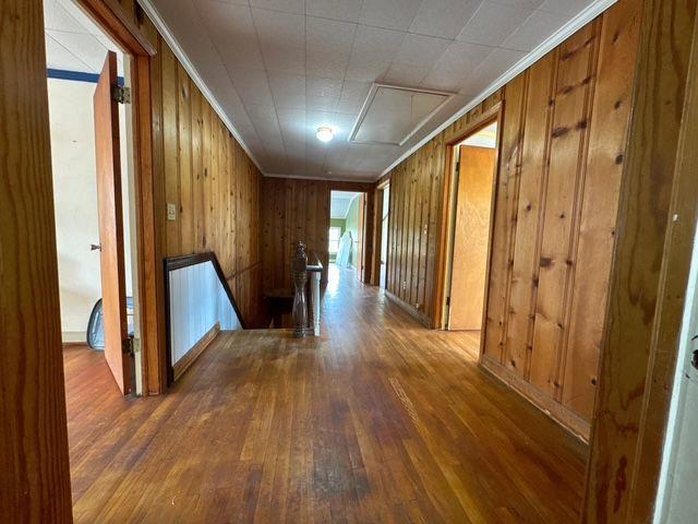 hall featuring dark hardwood / wood-style floors, wood walls, and ornamental molding