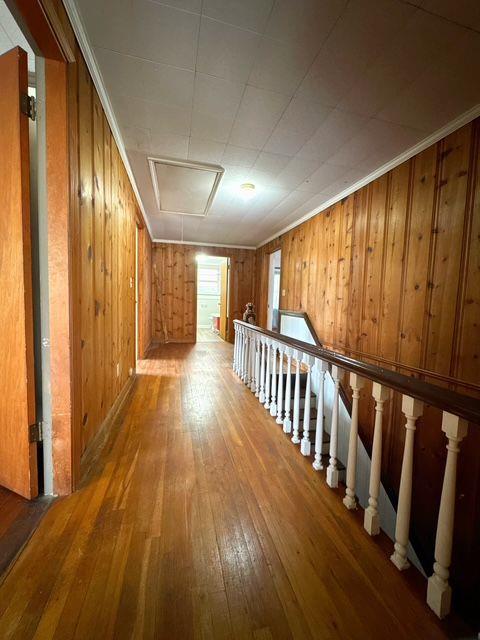 hall with hardwood / wood-style flooring, ornamental molding, and wood walls