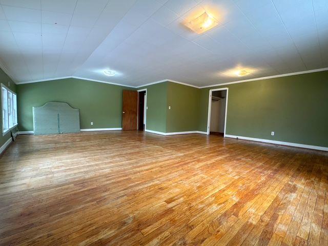 interior space featuring lofted ceiling, wood-type flooring, and crown molding