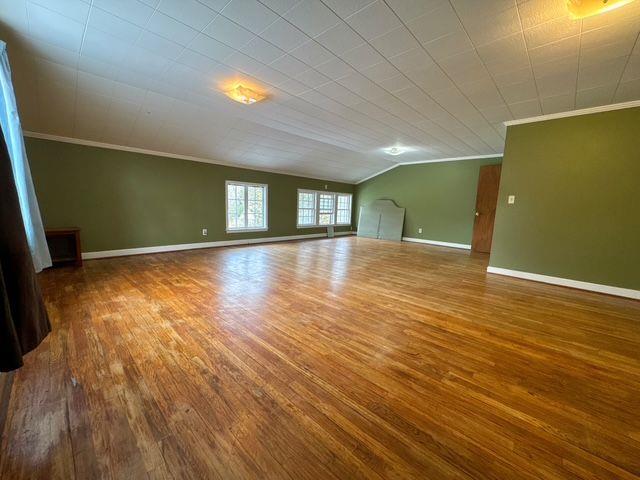 unfurnished living room with ornamental molding, vaulted ceiling, and hardwood / wood-style flooring