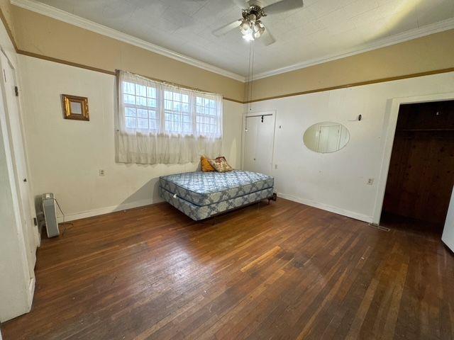 bedroom featuring ceiling fan, crown molding, and dark hardwood / wood-style floors