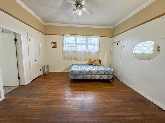 bedroom with ceiling fan, radiator heating unit, dark wood-type flooring, and ornamental molding