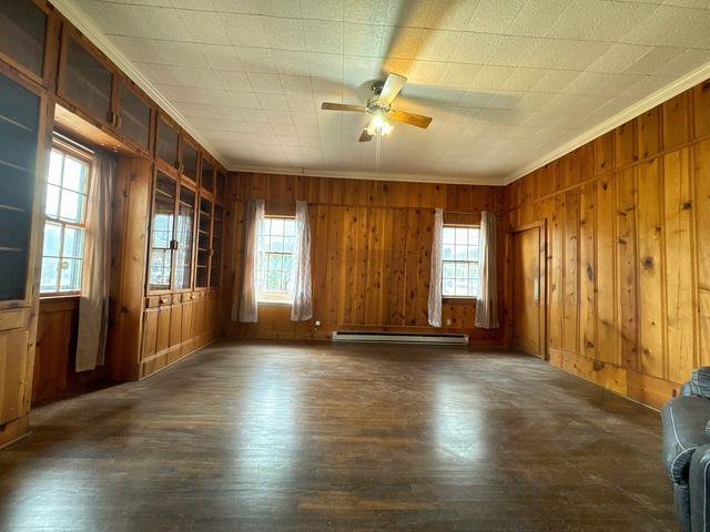 empty room with dark hardwood / wood-style floors, a healthy amount of sunlight, and wooden walls