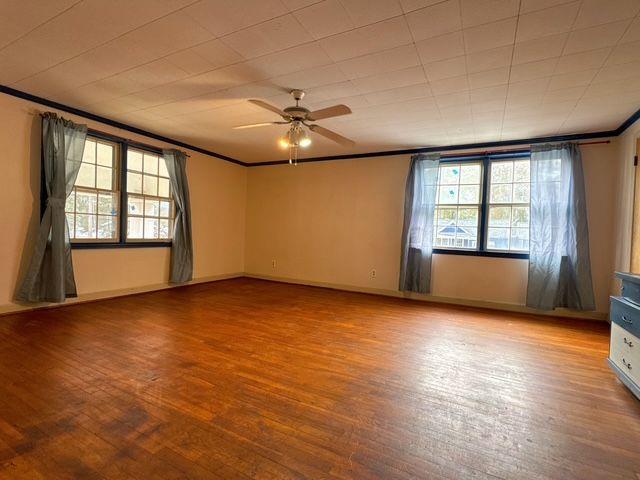 spare room with ceiling fan, wood-type flooring, and crown molding