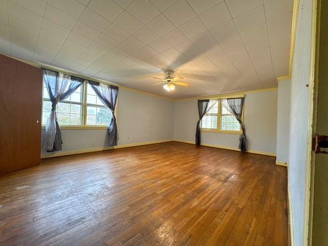 unfurnished room featuring wood-type flooring, a wealth of natural light, and ceiling fan