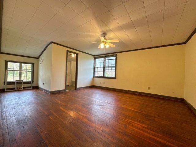 empty room featuring ceiling fan, dark hardwood / wood-style flooring, and crown molding