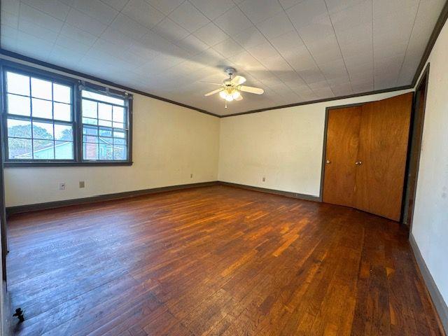 unfurnished room featuring dark hardwood / wood-style floors, ceiling fan, and crown molding